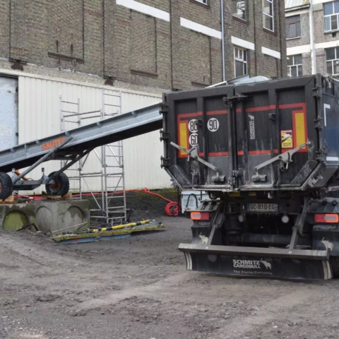 Un convoyeur de chantier utilisé pour transférer des gravats dans la remorque d'un camion.